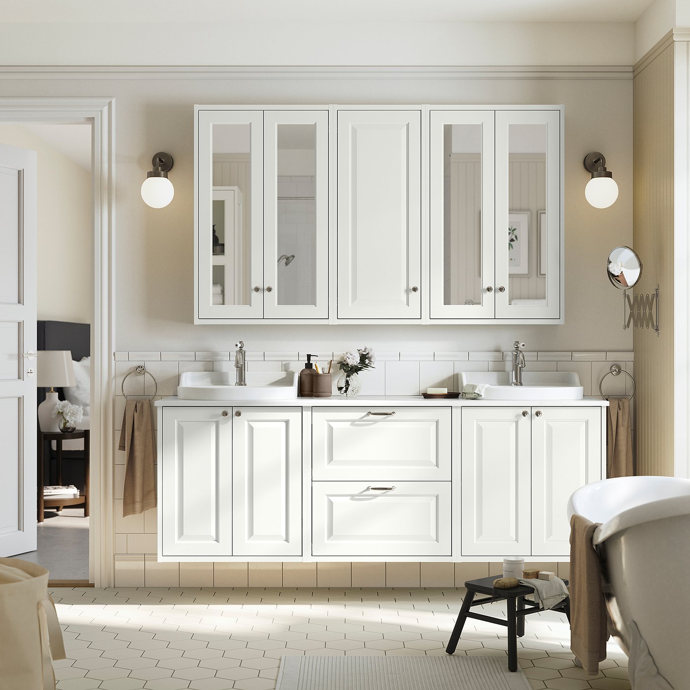 White TÄNNFORSEN vanity with large mirrors, two sinks, chrome fixtures, and ceramic top. Spacious storage, towels, and side table enhance modern look.