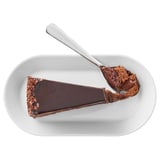 Slice of chocolate cake on white plate with spoon. Rich, creamy frosting; ideal for chocolate lovers.