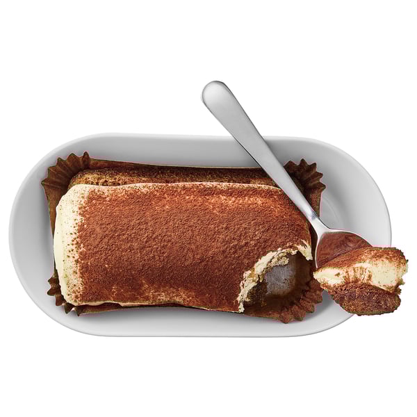 Dessert on plate, creamy with cocoa dusting, spoon taken bite.