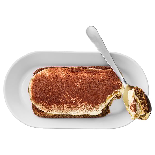 White plate with partially eaten rectangular dessert. Spoonful removed, revealing cream and biscuit layers.