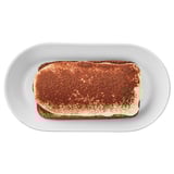 Rectangular plate holds layered dessert with cocoa dusting, likely tiramisu.