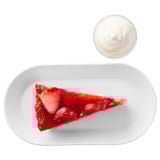 Strawberry cream tart slice on white plate with yogurt cup. Summer dessert with crunchy pastry base.
