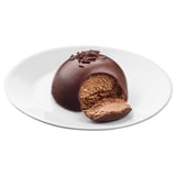 Chocolate cake on plate, cut open showing moist layers, with smooth ganache and shavings on top.