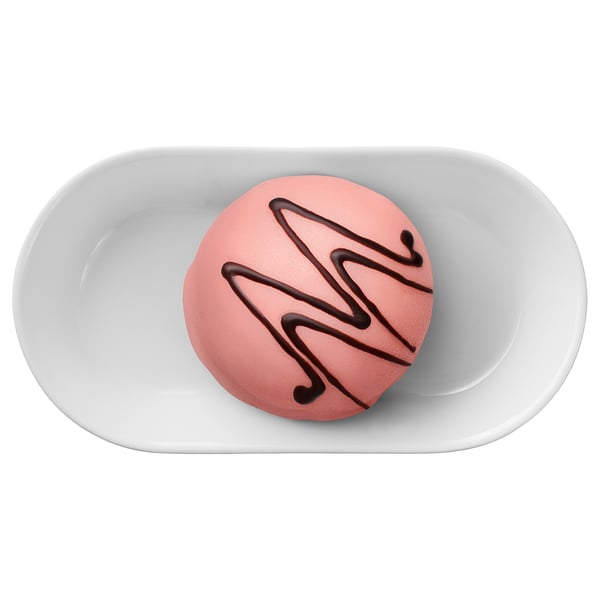 A light pink round pastry with chocolate swirls sits in a white dish.