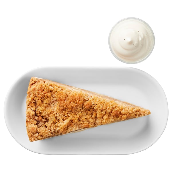 White plate with crumb cake slice and cup of cream. Dessert food item.