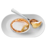 Stellen Sie sich ein Stück Kuchen auf einem Teller mit einer Gabel vor. Es ist ein kleiner, runder Kuchen mit einer glänzenden Glasur obendrauf, wahrscheinlich mit Mandeln und Zitrone aromatisiert.