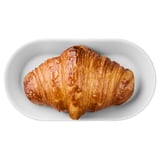 Un croissant doré avec des couches feuilletées repose sur une assiette blanche. Son extérieur croquant et son intérieur moelleux en font un régal délicieux.