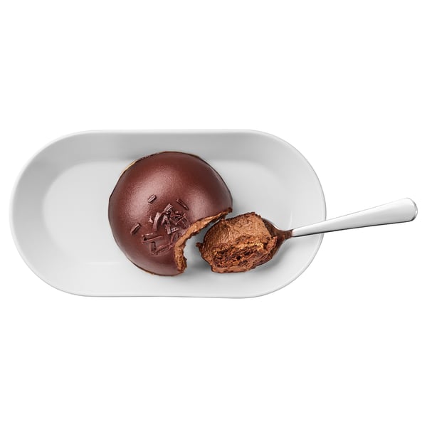 White plate with half-eaten chocolate dessert, spoon beside it. Rich, dense chocolate flavor with soft, airy cake beneath.