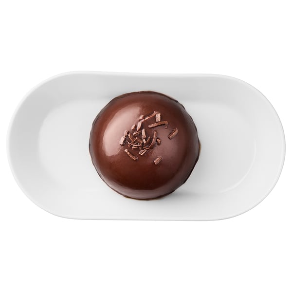 A chocolate mousse dessert on a white plate, topped with chocolate shavings.
