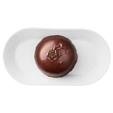 A chocolate mousse dessert on a white plate, topped with chocolate shavings.