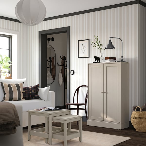Modern bedroom with light grey striped walls, a white sofa, wooden cabinet, and a stylish pendant lamp.