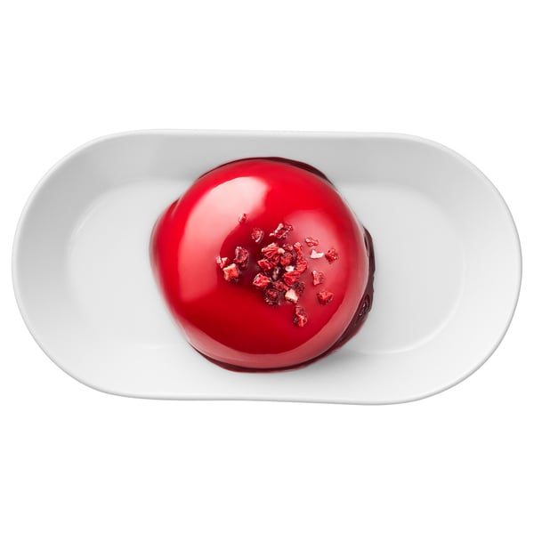 A round dessert with red glaze and raspberry pieces on a white plate.