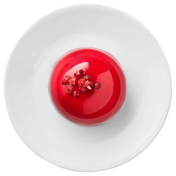 Round white plate with bright red dessert and small red decorations.