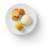 Image a white plate with breaded plant-based food, mashed potatoes, and corn.