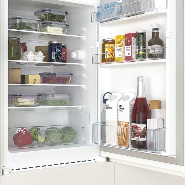 A well-organized mini fridge with transparent compartments, showing fresh vegetables, jars, and drinks. Adjustable shelves maximize storage.