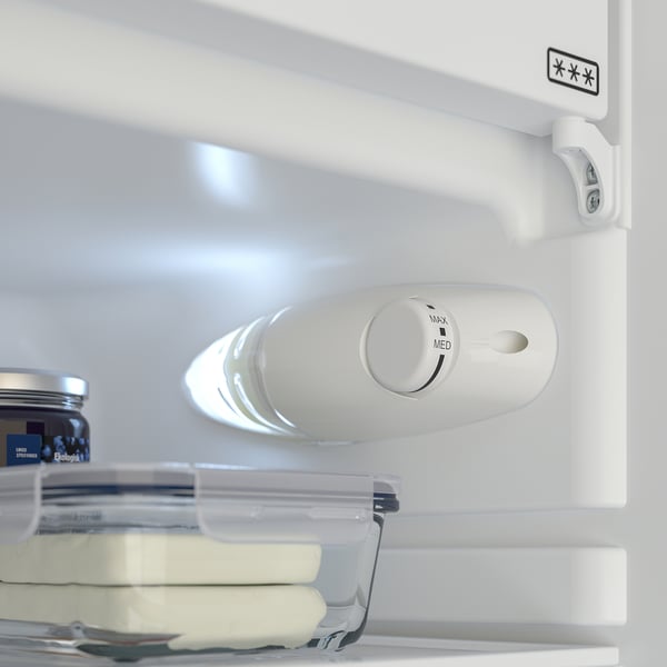 An open refrigerator with led light on. A dial for temperature control. A clear storage container with butter is visible.