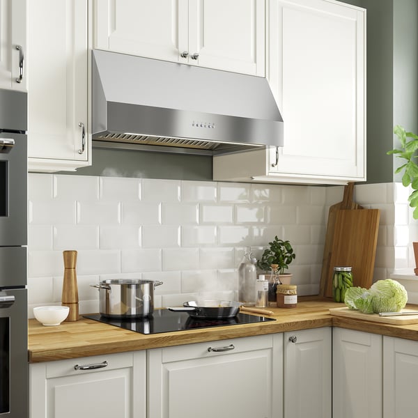 Kitchen with stainless-steel range hood, black cooktop, white subway backsplash, and wooden counters.