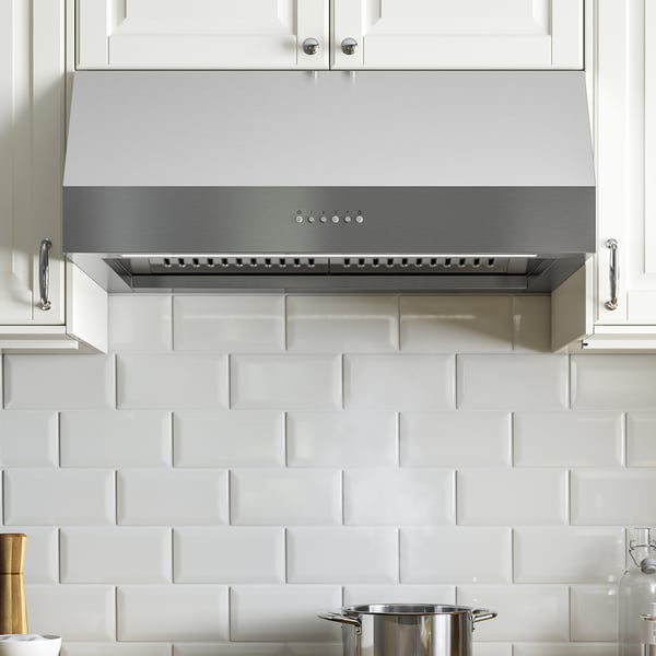 Modern kitchen with stainless-steel exhaust hood, featuring led lights and control panel, mounted under white cabinets with subway tile backsplash.