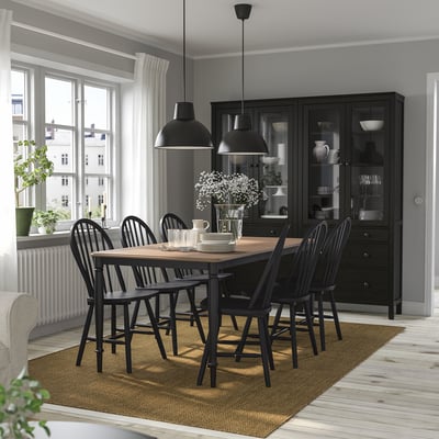 Wooden 6-seat dining set with classic black chairs. Fits between window and cabinet, with a cozy rug.