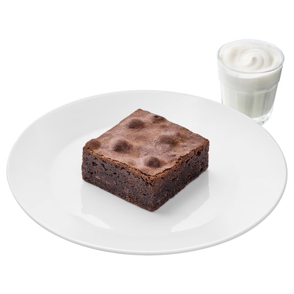 White plate with brownie, glass of white dessert sauce. Classic dessert treat