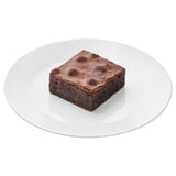 Square chocolate dessert on a white plate. Rich, dense texture, bittersweet flavor.