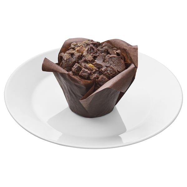 Chocolate muffin in tulip paper on white plate. Delicious dark, light, and white chocolate chunks. Soft, juicy inside.