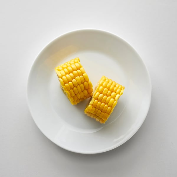 Two corn cob sections sit on a white plate.