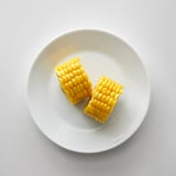 Two corn cob sections sit on a white plate.