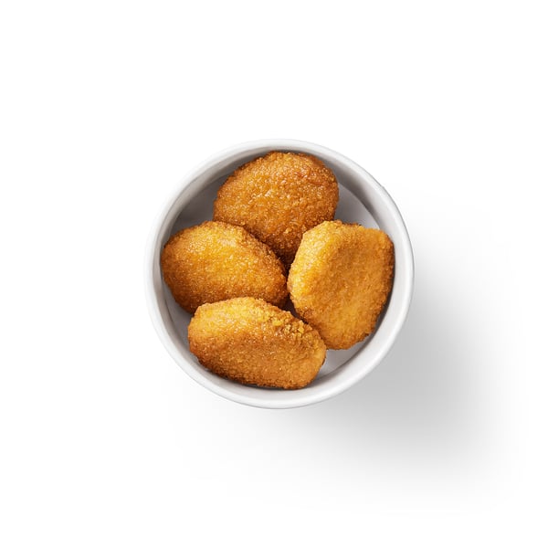 A bowl of five golden-brown, breaded plant-based nuggets on a white background.