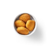 A bowl of five golden-brown, breaded plant-based nuggets on a white background.