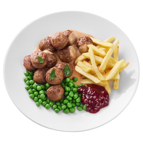 Piatto bianco con polpette, piselli, patatine fritte e ketchup.
