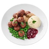 White plate with meatballs, peas, mashed potatoes, and gravy.