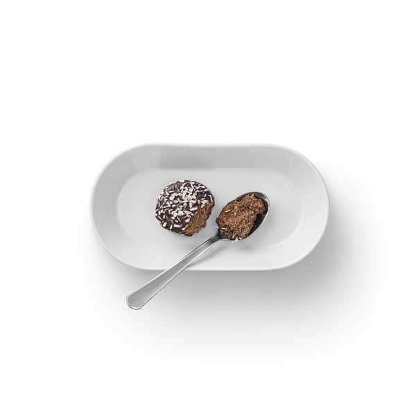 Un piatto bianco con due cucchiaiate di dessert al cioccolato e scaglie di cocco.