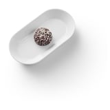 Un unico goloso tartufo di cioccolato su un piatto bianco. Spolverato con scaglie di cocco, presentato con eleganza.