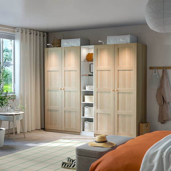 Wooden PAX wardrobe with shelves and drawers, with a straw hat and orange blanket nearby.