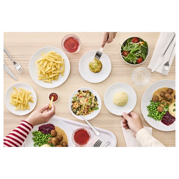 Mehrere Teller mit verschiedenem Geschirr und Besteck auf einem Tisch, bereit für eine Mahlzeit.