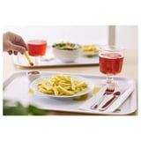 Eine Mahlzeit mit Pommes, einem Salat, Getränken und Besteck auf einem Tablett.