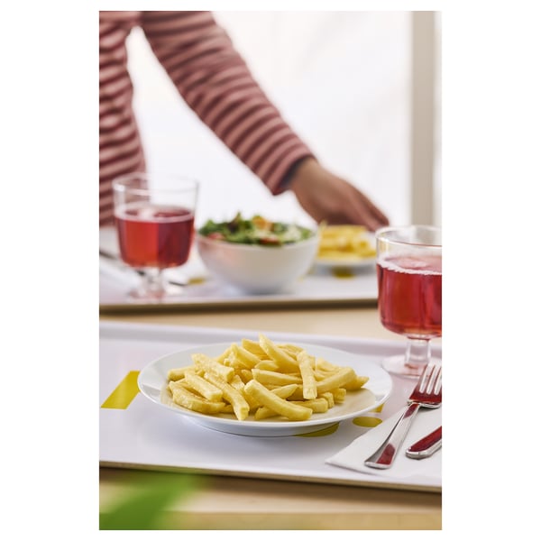 Eine Person, die Essen mit Getränken, Tellern und Besteck serviert, die auf einem Tisch stehen.