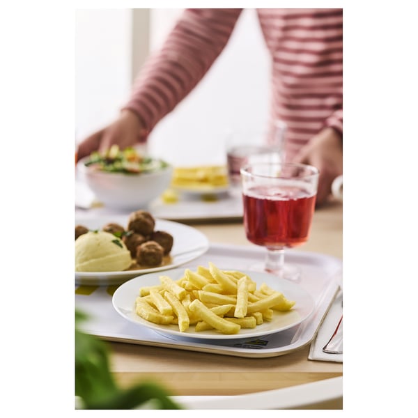 Ein Esstisch mit Tellern mit Essen und einem Glas rotem Getränk. Der Arm einer Person greift nach einer Schüssel.