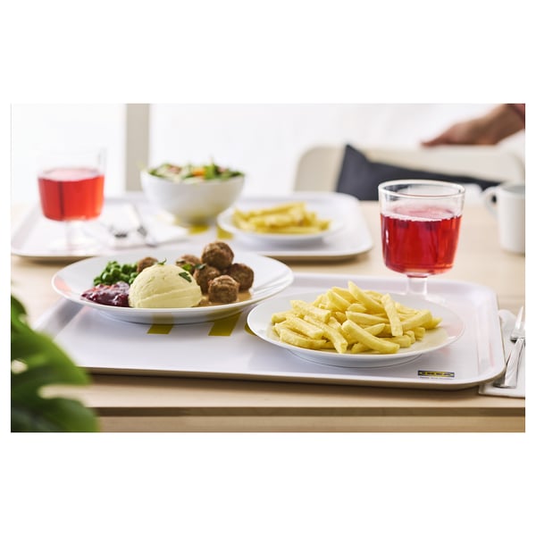 Weißes Tablett mit Tellern mit Fleischbällchen, Kartoffelpüree, Pommes, Salat und Getränken.