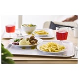 Weißes Tablett mit Tellern mit Fleischbällchen, Kartoffelpüree, Pommes, Salat und Getränken.