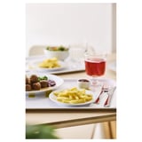 A meal setup on a table with plates of food, a glass of red juice, and cutlery.