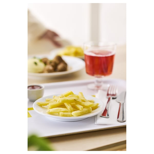 A meal with yellow food, a glass of red drink, and a fork on a white table.