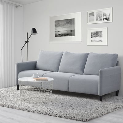 Szara 3-osobowa sofa, lampa, dywanik, stolik kawowy w przestronnym pokoju.