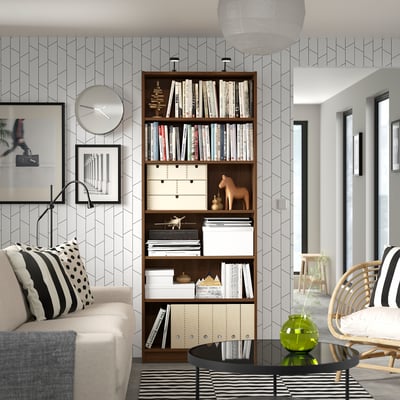 Nowoczesny salon z regałem BILLY, beżową sofą, czarnym stolikiem kawowym i ścianą w geometryczne wzory.