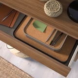 Biurko z otwartą szufladą mieszczącą długopisy, papier i notatnik.