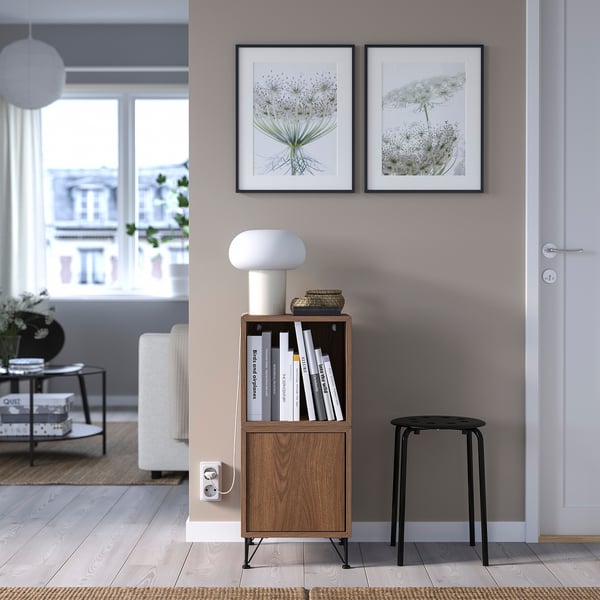 Nowoczesny salon z meblotą EKET, książkami, dekoracją, lampą, stołkiem i zdjęciami.