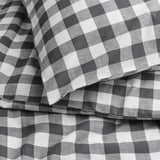 Czarno-biała tkanina w kratkę w kratkę, starannie złożona, prezentująca wyraziste wzory. Widoczna wysokiej jakości bawełniana faktura.