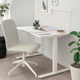 Krzesło biurowe ERFJÄLLET obok biurka z roślinami, lampą i książkami. Kompaktowa, elegancka konstrukcja.