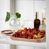 Drewniana taca z czerwonymi potpourri, pierścieniami i ozdobnymi butelkami. Zapewnia organizację i dodaje dekoracyjnego akcentu.